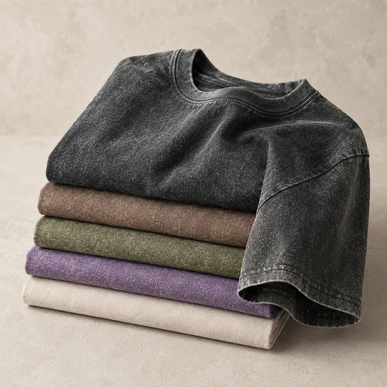 Stack of folded garment-washed 230GSM cotton tees in multiple colors